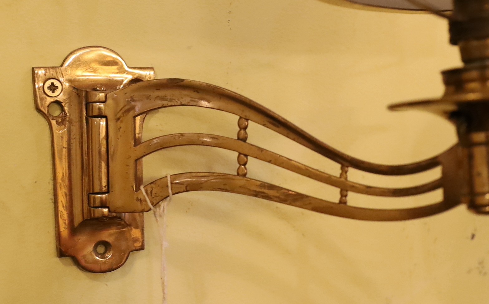 A pair of late Victorian brass swivelling wall lights with opaque glass shades, height 25cm. depth 25cm